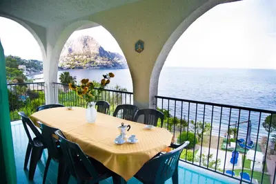 a table on a balcony with a view of the ocean at Villa Buonasera in Santa Flavia