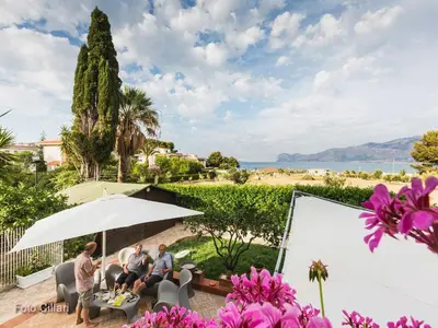 a group of three people sitting under an umbrella at Villa Matilde in Carini