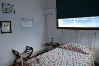 a bedroom with a bed and two chairs and a window at Villa Matilde in Carini