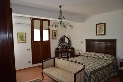a bedroom with a bed and a chair and a mirror at Villa Matilde in Carini