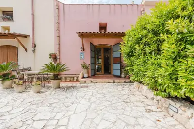 a pink house with a patio and plants at Villa 'Antico Baglio' - Scopello - Castellammare Del Golfo in Castellammare del Golfo