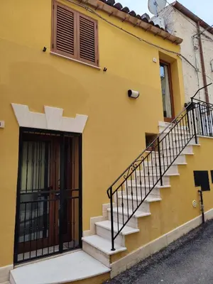 a yellow building with stairs next to a door at La Marina in Castellammare del Golfo