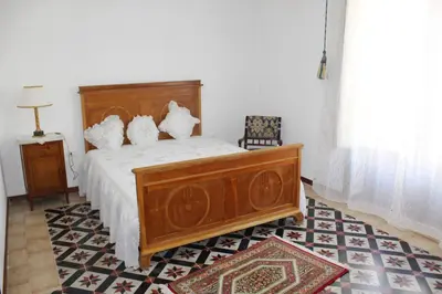a bedroom with a wooden bed with white sheets at Palazzo Taormina in Castellammare del Golfo