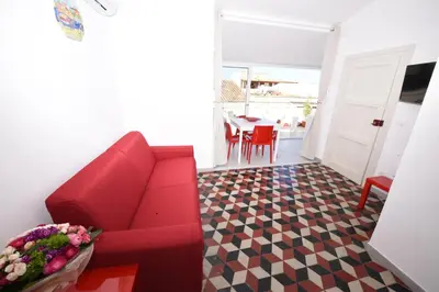 a living room with a red couch and a table at Palazzo Taormina in Castellammare del Golfo