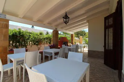 a patio with white tables and white chairs at B&B Villa Bea in San Vito lo Capo