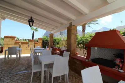 a patio with a table and chairs and a fireplace at B&B Villa Bea in San Vito lo Capo
