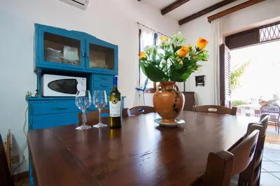 a table with two wine glasses and a vase with flowers at Villa Cala Bianca in Castellammare del Golfo
