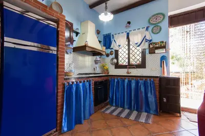 a kitchen with blue walls and blue curtains at Villa Cala Bianca in Castellammare del Golfo