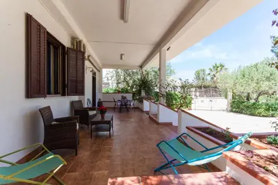 a room with chairs and a balcony with a patio at Villa Cala Bianca in Castellammare del Golfo