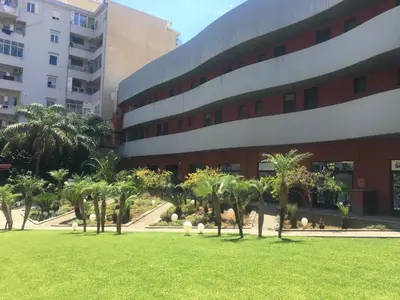 a park in front of a building with palm trees at Esmeralda Apartment in Palermo