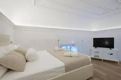 a white bedroom with a large bed and a flat screen tv at Politeama Apartments by Giorgio in Palermo