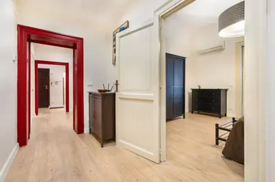a hallway with white walls and red doors and wooden floors at Casa Nonna Toto in Palermo