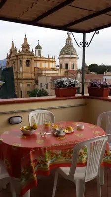 a table and chairs on a balcony with a view of a city at Le Casette in Santa Flavia