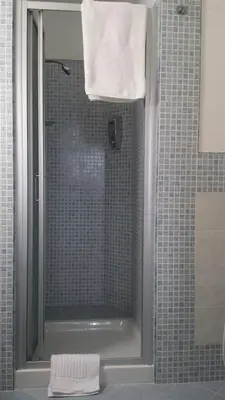 a bathroom with a shower with a glass door at Le Casette in Santa Flavia