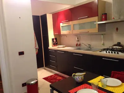 a kitchen with red cabinets and a sink and a table at La Casa Di Tufo in Palermo