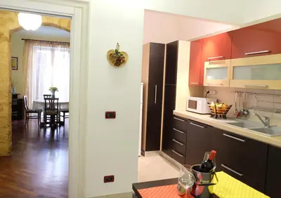 a kitchen with brown cabinets and a dining room at La Casa Di Tufo in Palermo