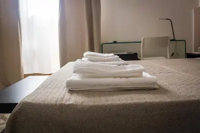 four white towels stacked on top of a bed at Liberty Suites in Palermo