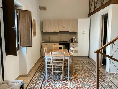 a kitchen with a table and chairs in a room at Nelle Antiche Mura in Castellammare del Golfo