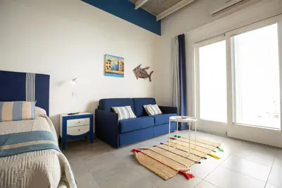 a bedroom with a blue couch and a bed at B&B Kolors in Castellammare del Golfo