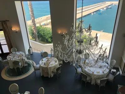 a dining room with two tables and a chandelier at Marina Holiday Hotel & Spa in Balestrate