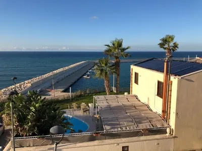 a building with a swimming pool next to the ocean at Marina Holiday Hotel & Spa in Balestrate