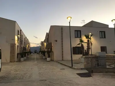 an empty street with buildings and palm trees in a city at Marina Holiday Hotel & Spa in Balestrate