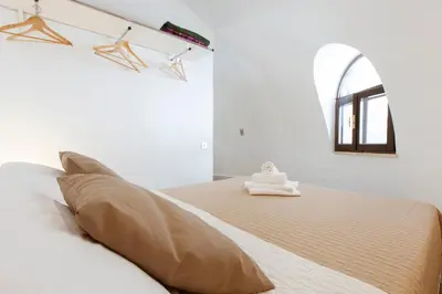 a white bedroom with a large bed and a mirror at Residence Guidaloca in Scopello