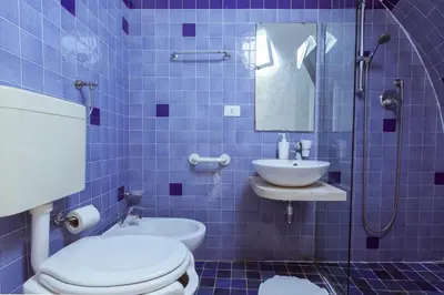 a blue tiled bathroom with a toilet and a sink at Residence Guidaloca in Scopello