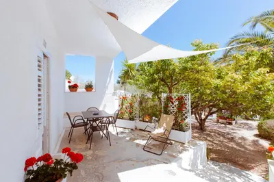 a patio with a table and chairs and trees at Residence Guidaloca in Scopello