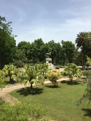 a park with palm trees and a statue in the distance at Casa Rosa in Palermo