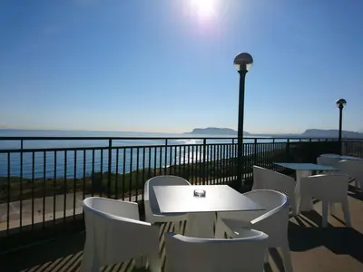 a table and chairs on a balcony overlooking the ocean at San Paolo Palace Hotel in Palermo