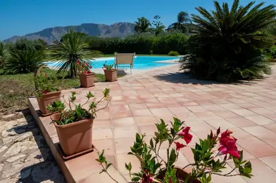a patio with potted plants next to a swimming pool at Villa delle Cecilie in Partinico