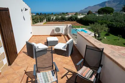 a balcony with two chairs and a table and a pool at Villa delle Cecilie in Partinico