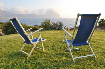 two chairs sitting on the grass near the ocean at Villa Tramonto in Macari