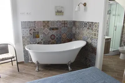 a white bath tub in a bathroom with tiles at Dimore de La Rosa in Palermo
