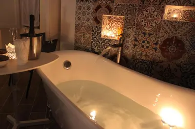 a bath tub in a bathroom with a table and a lamp at Dimore de La Rosa in Palermo