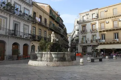 a statue in the middle of a street with buildings at Dimore de La Rosa in Palermo