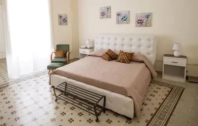 a bedroom with a large bed and a chair at La Cubba in Palermo