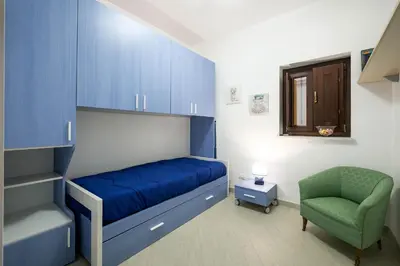 a bedroom with a blue bed and a green chair at Casa Petra ai Quattro Canti in Palermo