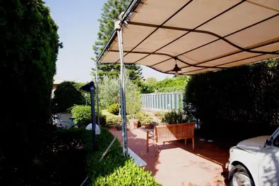 a patio with a tan umbrella and a bench at Siciliaiu in Mondello