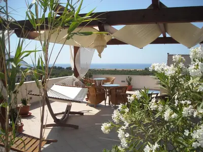 a patio with tables and chairs and an umbrella at Karma B&B in San Vito lo Capo