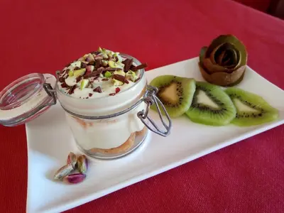 a dessert in a jar on a plate with kiwi and nuts at Karma B&B in San Vito lo Capo