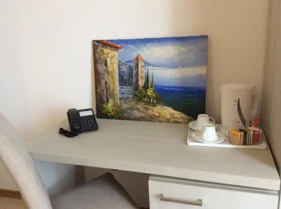 a desk with a phone and a painting on the wall at Artemisia Palace Hotel in Palermo
