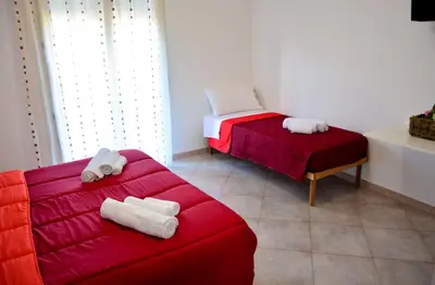 a room with two beds and a red couch at Sui tetti b&b in Alcamo