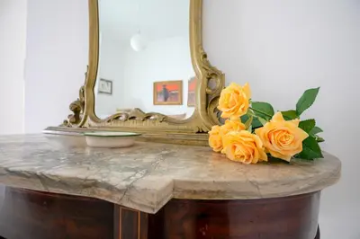 a table with a mirror and a bouquet of orange roses at Appartamento Piazza Pretoria in Palermo