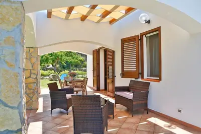 a patio with chairs and tables and a stone wall at Verdemare in Cefalù