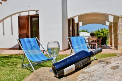 two chairs and a bottle of wine and a glass at Verdemare in Cefalù