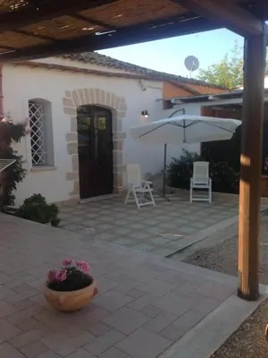 a patio in front of a house with an umbrella at Lovely Cottage in Castellammare del Golfo