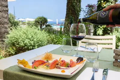 a plate of food on a table with a glass of wine at Domina Zagarella Sicily in Santa Flavia