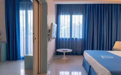 a hotel room with a bed and blue curtains at Domina Zagarella Sicily in Santa Flavia